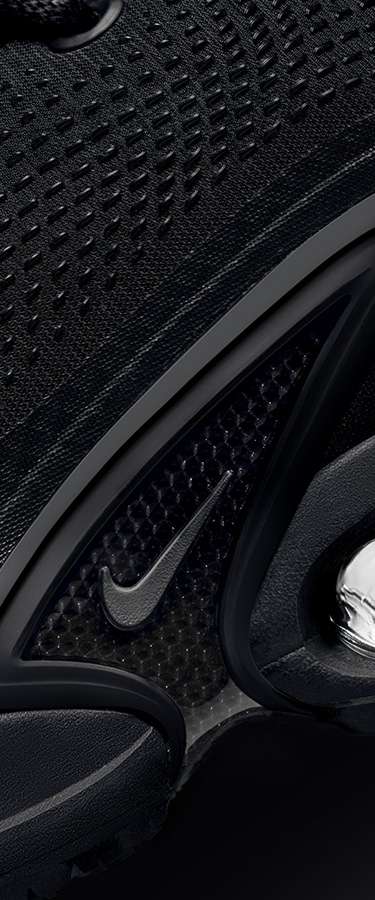 Immagine in primo piano, con logo Nike Swoosh rosso messo a fuoco su uno sfondo testurizzato che passa gradualmente dal viola al nero, che mostra una sezione del design di una sneaker.