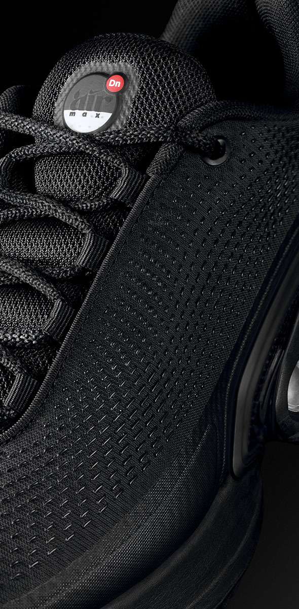 A close-up of a black textured fabric with a pattern of uniform perforations.